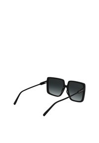 Lunettes de soleil carrées noires avec des verres gris dégradés, finition mate et branches noires fines. Présentent un logo discret sur une branche.