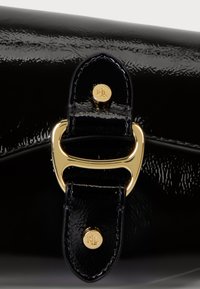 Fekete, lakkbőr táska fényes felülettel, arany fémből készült záróelemmel és logó részlettel a hozzáillő bőrszíjon.