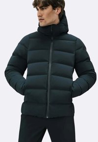 Giacca a vento nera con chiusura a zip, caratterizzata da un collo alto e un motivo trapuntato orizzontale per isolamento e texture.