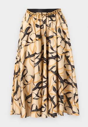 Jupe plissée beige avec imprimé chaîne noire et or, ceinture noire à la taille et ceinture décorative en chaîne dorée.