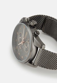 Montre en acier inoxydable noir avec un bracelet en maille, un cadran gris, des accents en or rose et trois sous-cadrans. Présente une fenêtre de date à 3 heures.