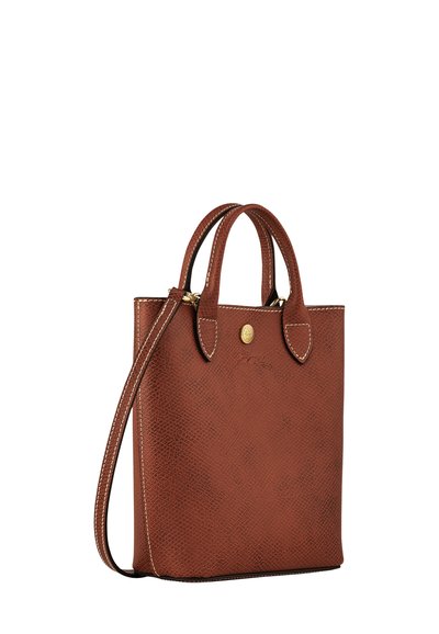 Braune Leder-Tote mit strukturierten Oberflächen, goldenen Beschlägen, kurzen Griffen und einem abnehmbaren Schultergurt. Akzentnaht entlang der Kanten.