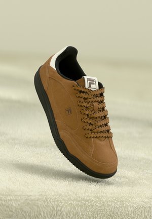 Brown suede sneaker with black rubber sole, thick laces, and white accents at the heel. Logo featured on the tongue.