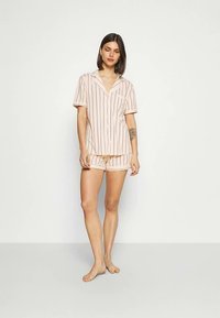 Ensemble de pyjama rose clair à rayures verticales, composé d'une chemise à manches courtes et d'un short assorti, fabriqué en tissu doux. Détail notable avec une poche.