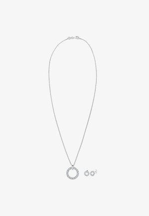 Collana in argento con un pendente circolare adornato di pietre trasparenti, accompagnata da orecchini a bottone coordinati con un design simile delle pietre.