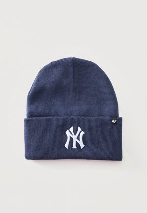 Тъмносиня плетена шапка с подгънат ръб, бяло лого на New York Yankees и малък етикет на марката 47.