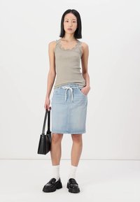 Grå ribbestrikket tanktop med blonder, lyseblå denim blyantskjørt, svarte plattformloafers, og en strukturert svart håndveske.