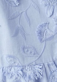 Tissu blanc avec broderie florale texturée mettant en valeur des feuilles et des fleurs dans différents motifs de points et des détails de fils en relief.