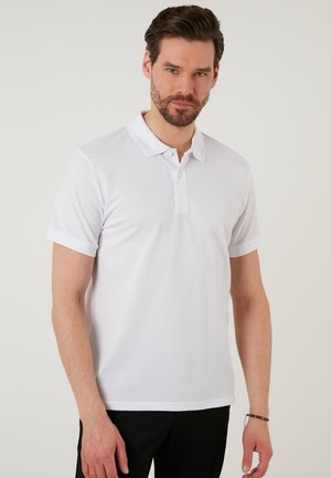 Valkoinen polo paita, jossa on teksturoitu kangas, lyhyet hihat ja klassinen kauluskorkeus. Ominaisuuksiin kuuluu kolme nappia kaulassa ja slim fit -muotoilu.