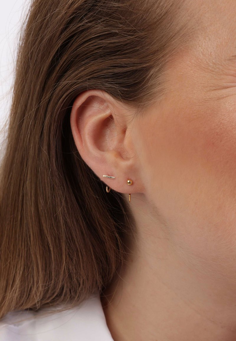 Boucles d'oreilles en or avec un petit billes, une tige et un design en anneau. Les matériaux sont brillants, avec une texture lisse, mettant en valeur des formes modernes.
