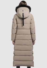 Bézs színű, hosszú pufi kabát fekete, műszőrme bélésű kapucnival, steppelt textúrával és kontrasztos fekete fém kiegészítőkkel. Cipzáras oldalsó zsebek.