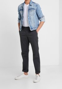 Džínová bunda světle modré barvy, bílé tričko, tmavě šedé kalhoty a bílé tenisky. Bunda má dvě kapsy na prsou a ohrnuté rukávy.