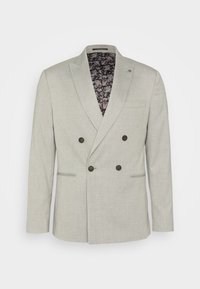 Světle šedý dvouřadý blazer s texturovanou tkaninou, který má tmavé knoflíky a vzorovanou černou podšívku. Dvě přední kapsy.