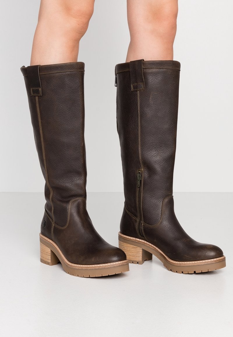 Tmavě hnědé kožené kozačky nad kolena s texturovaným povrchem, opatřené bočním zipem a dřevěným blokovým podpatkem s gumovou podrážkou.