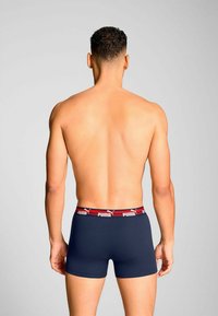 Men's navy boxer shorts with a red and white waistband featuring the Puma logo. Soft fabric, fitted design, and smooth texture.