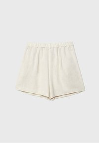 Shorts en lin beige avec une taille élastique, présentant une coupe ample, des plis plats à l'avant et un design simple et minimaliste.