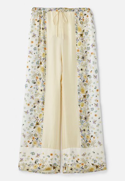 Floral-patterned wide-leg pants feature a light yellow base with white floral designs in purple, orange, and green accents. Adjustable waistband.