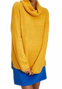 Gul stickad tröja med ringkrage och långa ärmar, kombinerad med en blå kjol. Texturen är ribbad och passformen är lös.