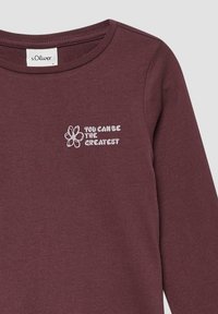 Bordeauxfarbiges Langarmshirt mit Rundhalsausschnitt, bestickter weißer Blume und dem Text "DU KANNST DER GRÖßTE SEIN" auf der Brust.