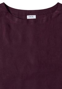 Chemise en lin violet foncé avec un col rond et une étiquette blanche indiquant "CECIL" cousue à l'intérieur du col arrière.