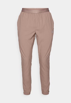 Light pink jogger pants with an elastic waistband and cuffs, made from a smooth, lightweight fabric. Features side pockets and subtle branding.