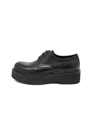 Scarpe platform nere in pelle con punta rotonda, con lacci sul davanti e suola in gomma spessa. Texture liscia e dettagli di cucitura sottili attorno alla suola.