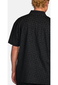 Short-sleeve black shirt with a textured pattern of stars. Featuring a collar and a relaxed fit, crafted from lightweight fabric.