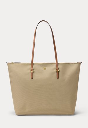Sac cabas beige avec des anses d’épaule en cuir marron, des éléments métalliques dorés, une fermeture éclair sur le dessus et un petit logo doré à l’avant.