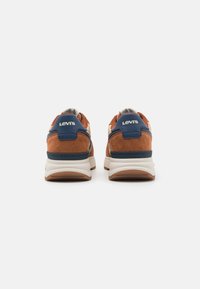 Smeđe suede tenisice s mornarskoplavim naglascima, bijelim međuslojem i smešnim gumiranim potplatom. Sadrži "Levi's" logo na peti.