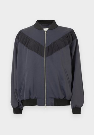 Tmavě modrá bomber bunda z lehké látky, vybavená zipem, žebrovanými manžetami a designovým akcentem v podobě černého volánkového panelu.