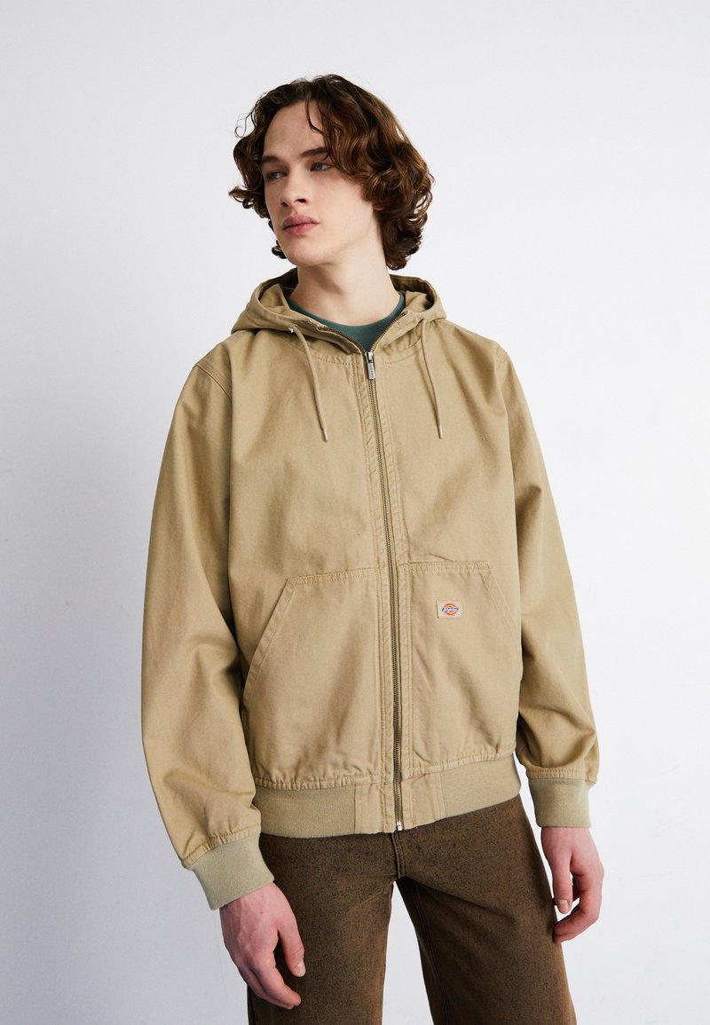 Bežna zip-up kapuca z vrvico na kapuci, veliki sprednji žepi, rebrasti manšeti in majhen logotip na levi strani.