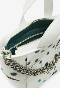 Borsa bianca con pois turchesi, dotata di manico a catena e chiusura con zip. Interno foderato in verde scuro con tasche aggiuntive con zip.