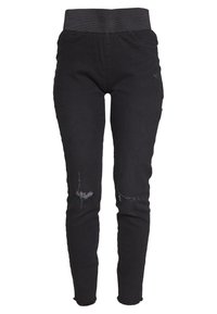 Jean skinny en denim noir avec une taille haute élastique, présentant des zones genoux usées et une silhouette ajustée, avec un ourlet légèrement effiloché.