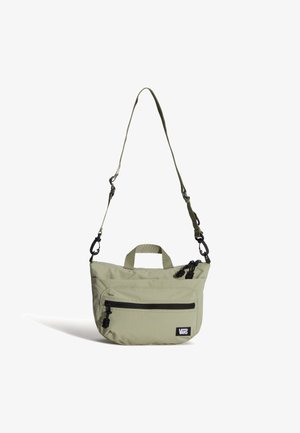 Bolso bandolera de Vans verde claro con bolsillo frontal con cremallera, tiradores de cremallera negros y correa ajustable sobre fondo blanco.