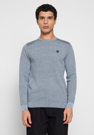 Lichtblauwe gebreide trui met een gestructureerd patroon, geribbelde manchetten en accenten op de schouders. Voorzien van een klein embleem op de borst.