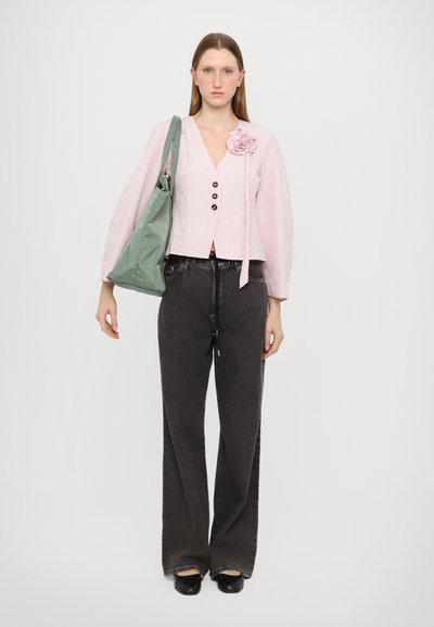 Randig rosa blus med en blommig accent, bruna knappar och ett band; matchad med mörka vida jeans och en grön tygväska.