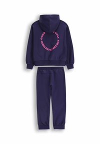 Granatowy dres z kapturem. Na tyle bluzy z kapturem znajduje się różowy okrągły napis. Rękawy zakończone mankietami oraz spodnie w stylu jogger.