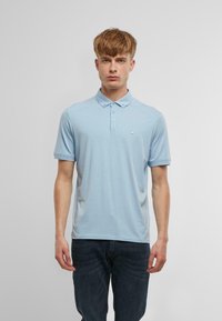 Gaiši zils polo krekls ar īsām piedurknēm, ar pogājamu apkakli un mazu logotipu uz krūtīm; gluda auduma, regulāra piegriezuma.