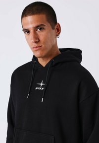 Felpa nera con cappuccio, tasca frontale, cordoncino e logo argento "PXF" sul petto. Realizzata in tessuto morbido con una vestibilità comoda.