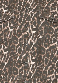 Tissu à imprimé léopard marron et noir avec boutons-pression noirs et poches à rabat sur un vêtement.