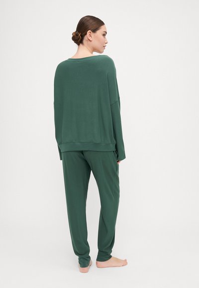 Conjunto de roupa de lazer verde, com uma blusa de manga longa de corte solto e calças justas, ambos em um tecido suave e texturizado, com costuras mínimas.