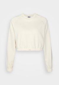 Kortärmad cremefärgad sweatshirt med långa ärmar, elastisk nederkant och muddar. Har en vit logotyp på bröstet. Mjuk, texturerad tyg.