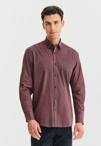 Bordowa koszula z długim rękawem z kołnierzykiem zapinanym na guziki, wykonana z teksturowanej tkaniny, z granatowymi guzikami i subtelnym geometrycznym wzorem na całej powierzchni.