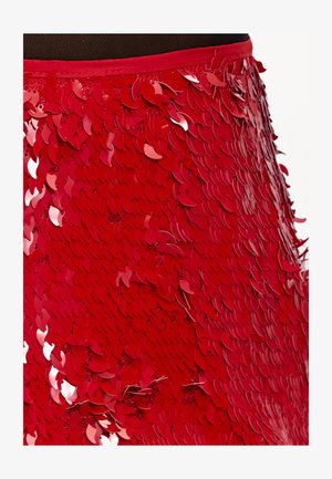 Jupe en sequins rouges ornée de sequins superposés en forme de feuilles avec une finition brillante. Ceinture lisse de couleur vive avec une surface texturée.