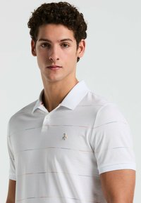 T-shirt polo blanc avec des rayures pastels horizontales, manches courtes et un petit logo brodé sur la poitrine gauche. Tissu léger.