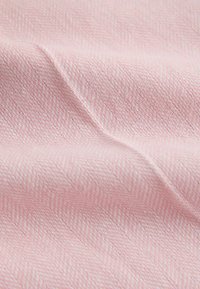 Mekana ružičasta tkanina s neprimjetnim ribljim kosturim uzorkom i nježnim naborima koji stvaraju teksturu i dubinu.