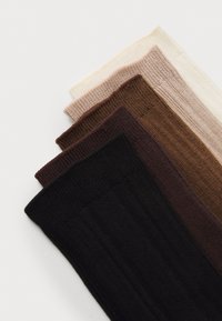 Cinco pares de calcetines acanalados en tonos variados: beige claro, rosa suave, marrón medio, marrón oscuro y negro. Cada uno presenta un punto texturizado.