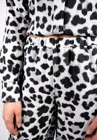 Black and white leopard print shirt and trousers in soft fabric, featuring button details, elastic waistband, and relaxed fit.