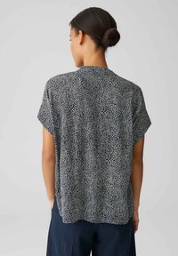 Blusa a maniche corte in tessuto leggero, caratterizzata da un motivo astratto blu navy e bianco, vestibilità rilassata e scollatura rotonda.