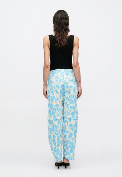Χαλαρά παντελόνια από υφαντό ύφασμα σε φωτεινά μπλε και κρεμ με σχέδιο, με φαρδύ κόψιμο και τσέπες, συνδυασμένα με μαύρο αμάνικο τοπ.